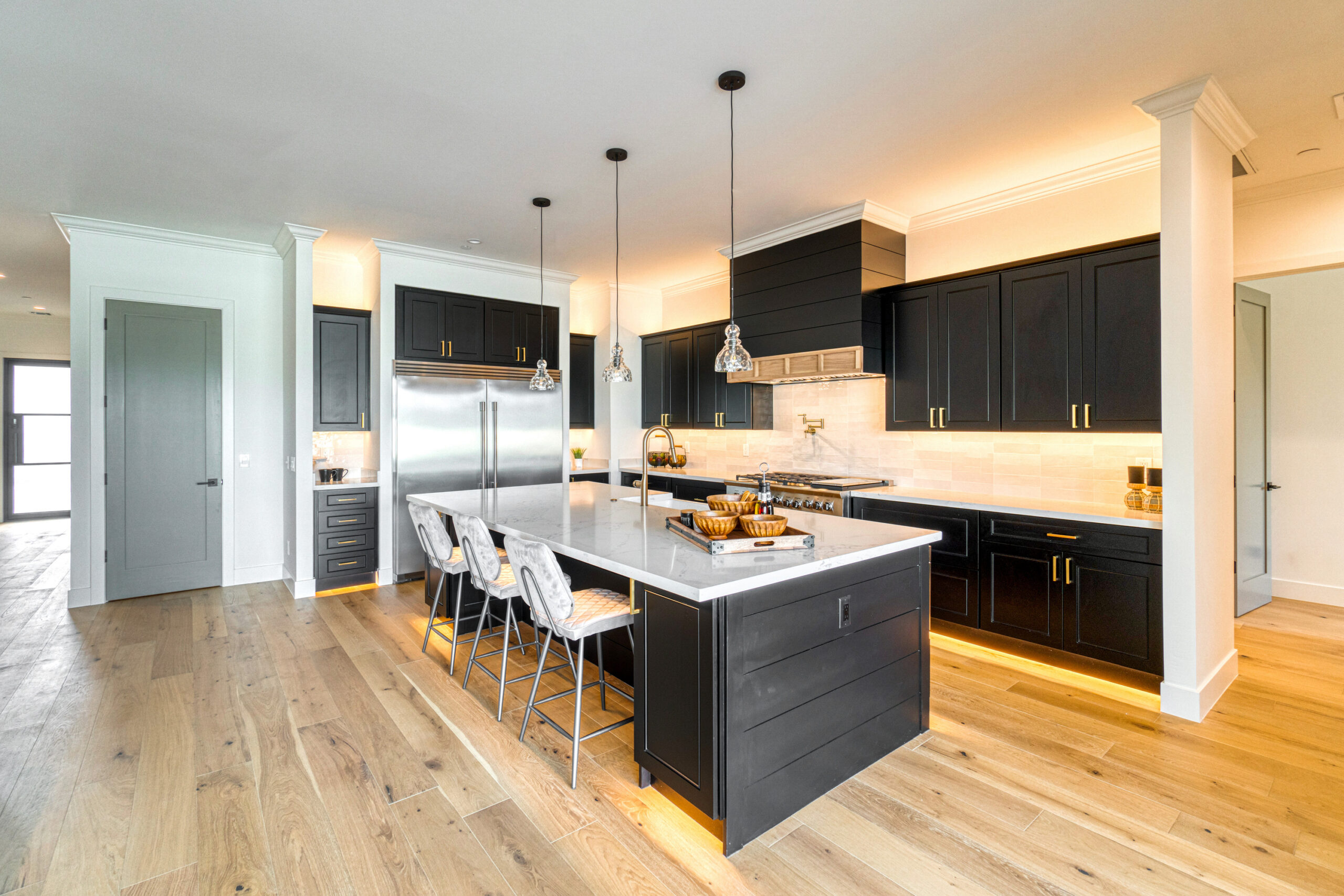 A finished kitchen with dark cabinetry and a bright island